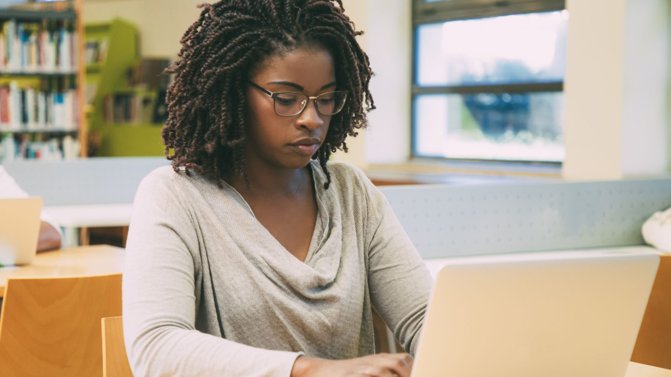 A medical school student taking an NBME practice exam in a library on her laptop.